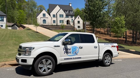 White Ford pickup truck with Home Pros Plus branding parked in front of a large residential house on a sunny day